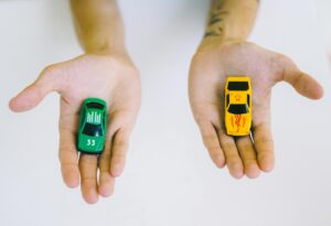 2つの手のひらにそれぞれ異なるミニカーを乗せて比較しているイメージ